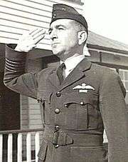 Half portrait of man in dark military uniform with forage cap, saluting