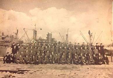  1071st Engineer Port Repair Ship Crew, with the Junior N. Van Noy in the background.