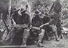 Military officers review maps in a jungle setting