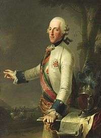 Painting shows a man in a 18th century white wig, gesturing at a distant battle with his right hand while his left hand rests on a map table. He wears a white military coat with dark blue cuffs and a sash across his right shoulder.