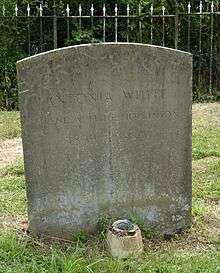 A granite headstone in a grassy churchyard