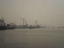 port quayside can be seen shrouded in hazy fog, obscuring cranes and piers