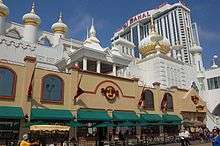 The facade of the Trump Taj Mahal, a casino in Atlantic City. It has motifs evocative of the Taj Mahal in India. A tall building with the resort's name stands in the background.