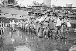 Soldiers disembark from a troopship at a dock