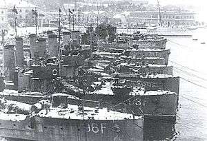 a black and white photograph of several ships at a dock