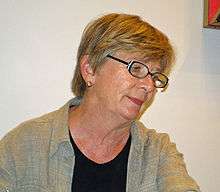 Woman with dark glasses and short hair facing right