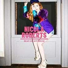 A red haired woman wearing a colored dress sitting on a window. In front of her, it is written "NICOLA ROBERTS BEAT OF MY DRUM" in pink.