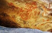 Red rock paintings of humans and humans on horses.