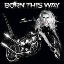 Grayscale image of a bike against a black background. The bike has a blond woman's head at its front, whose right hand stretches out to the front tires of the bike. The words "Born This Way" is embossed above the image.