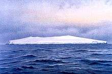  A low ice-covered island in blue choppy water, under a heavily clouded sky