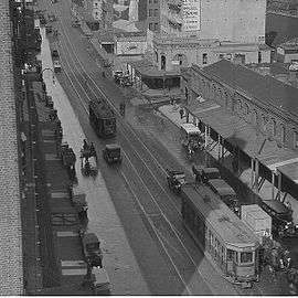 View down street with cars and trams