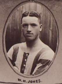 Head and upper torso of a stocky white man with dark hair parted in the middle. He is wearing a sports shirt with broad stripes.