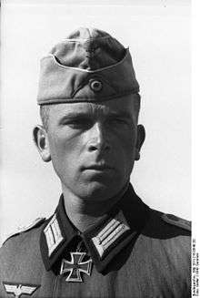 Black-and-white portrait of a man with a military uniform, side cap and an Iron Cross displayed at his neck.