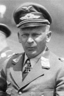The head and shoulders of a man, shown in semi-profile. He wears a peaked cap and a military uniform with an Eagle above his right breast pocket, and an Iron Cross displayed at the front of his white shirt collar.