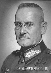 A man with short hair wearing glasses and a military uniform.