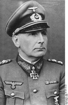 The head and shoulders of an elderly man, shown in semi-profile. He wears a peaked cap and a military uniform with an Eagle above his right and various military decorations above and on his left breast pocket, and an Iron Cross displayed at the front of his shirt collar. His facial expression is a determined; his eyes are looking into the distance to the left of the camera.