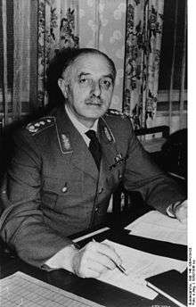 A man wearing a military uniform sitting at a desk.