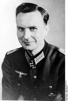 A black-and-white photograph of a smiling man wearing a military uniform and neck order in shape of an Iron Cross.