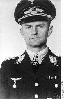 A man wearing a peaked cap and a military uniform with an Iron Cross displayed at the front of his uniform collar.