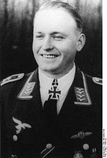 A smiling man wearing a military uniform and an Iron Cross displayed at the front of his uniform collar.