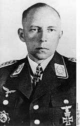 Black-and-white photo of a man wearing military uniform with various military decorations including an Iron Cross at his neck.