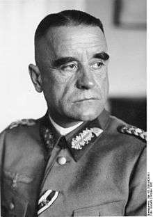 A black-and-white photograph of an older man in semi profile wearing a military uniform. His eyes are looking to the left of the camera