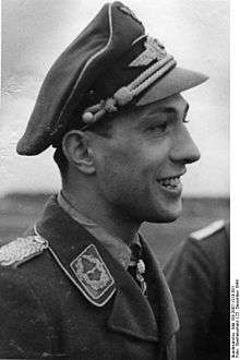 A man wearing a military uniform with a peaked cap on his head.