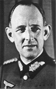 A black-and-white photograph of a smiling man wearing a military uniform.
