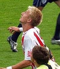 A man with blond hair who is wearing a white and red striped shirt.