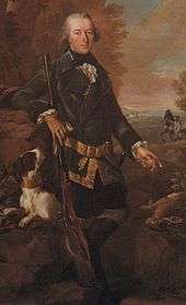 Full length portrait of a man in a dark coat holding a rifle about four and a half feet long with his dog