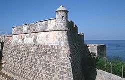 The top of a wall that appears to belong to an old castle. The sea is visible in the distance.