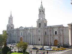 Facade of a very large white church with two tall towers.