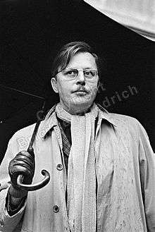 man with glasses in raincoat and umbrella looking right