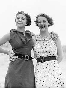 two young women in sleeveless dresses hugging