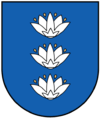 A coat of arms depicting three white flowers lined up vertically with four yellow seeds surrounding each all on a blue background