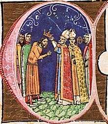 A bishop puts a crown on the head of a bearded man