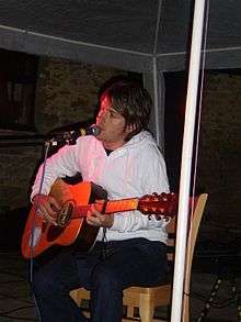 A man sits on a chair playing a guitar