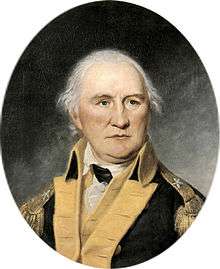 Portrait shows a determined-looking white-haired man in a dark blue military coat with buff lapels.
