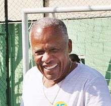 Middle-aged man smiling, with a football goal in the back