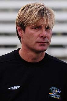A man with blonde hair who is wearing a black top.