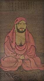 A seated monk in a red robe.