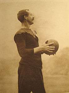 Image of Gallaher wearing his black rugby uniform and clasping a football.