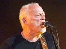 Gilmour singing into a microphone onstage
