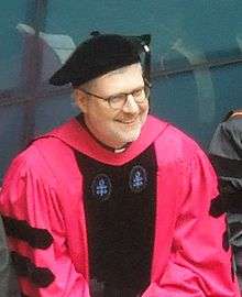 Holtschneider smiling, wearing graduation robes and a cap
