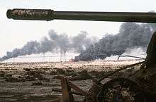 Burning oil field, framed between the body and gun of a wrecked tank