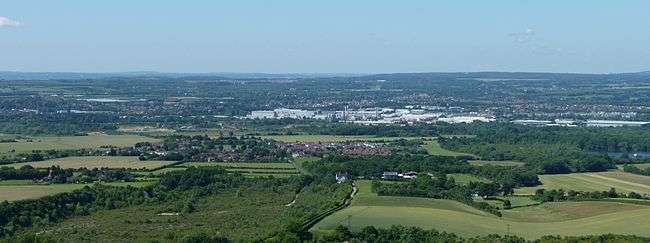 A panoramic photograph of the view across a wide river valley with areas of countryside mixed with buildings