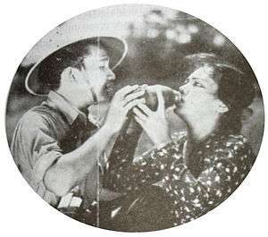 A promotional image showing a woman in a polka-dotted shirt receiving water from a man in a safari hat.