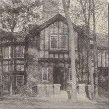  A two story Tudor style building in a forest of tall trees
