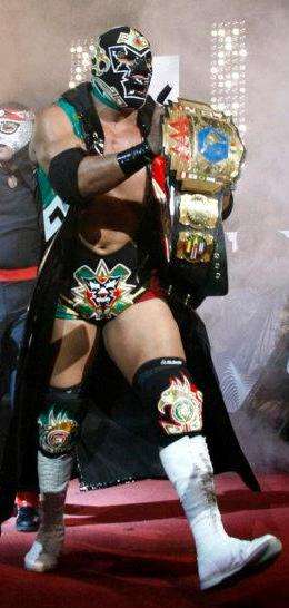 Masked wrestler Dr. Wagner Jr. walking to the ring, holding the AAA Latin American Championship belt up in the air.