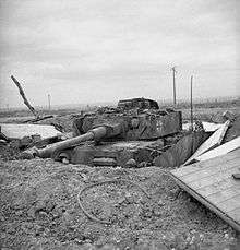 A frontal view of a knocked out German tank in a hull-down position, protected by earth entrenchments.